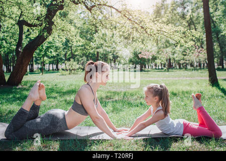 Le ragazze si trovano faccia a faccia e in contatto tra loro le mani. Si stanno mantenendo la loro superiore-corpo fino quando sono sdraiato sul carimate con il loro basso Foto Stock