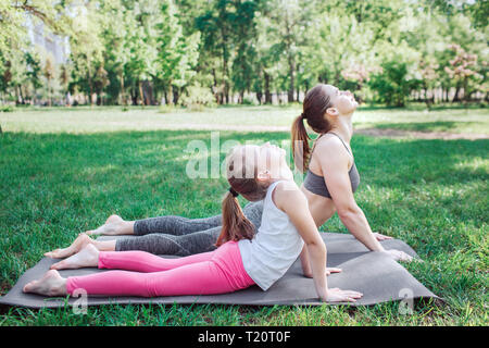 Due persone di sesso femminile sono giacenti su carimate e stirando il loro corpo superiore. Essi stanno cercando di raggiungere il retro con le loro teste Foto Stock