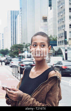 Una donna afro-brasiliana in Sao Paulo utilizzando il suo telefono in strada Foto Stock