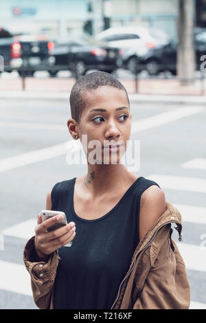 Una donna afro-brasiliana in Sao Paulo utilizzando il suo telefono in strada Foto Stock