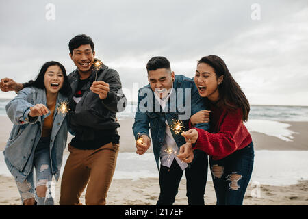 Gruppo di amici asiatici divertendosi con botti in spiaggia. Un gruppo di giovani uomini e donne che celebra il giorno di Capodanno presso la spiaggia. Foto Stock