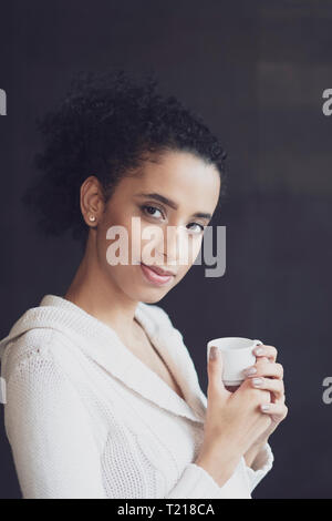 Un giovane Afro donna latinoamericana tenendo la sua pausa caffè Foto Stock