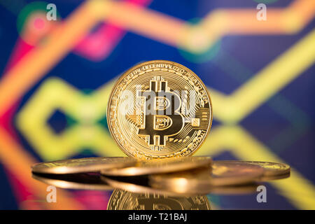 Golden bitcoin sono impilati su uno sfondo luminoso di grafici aziendali close-up. Bitcoin cryptocurrency Foto Stock