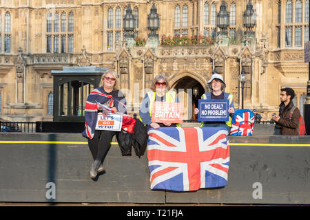 Londra, Regno Unito; 29 marzo 2019; tre femminili Pro-Brexit dimostranti sedersi sulla barriera di sicurezza al di fuori del Parlamento tenendo Pro-Brexit segni e Union Jack Flag. Foto Stock