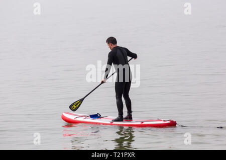 Branksome Dene, Poole, Dorset, Regno Unito. 30 Mar, 2019. Regno Unito: meteo nebuloso il sole di mattina e lo scambiatore di calore del ritardo, ma non interrompere i visitatori diretti al mare a Branksome Dene. L'uomo paddleboarding. standup paddleboarder standup paddle boarder Credito: Carolyn Jenkins/Alamy Live News Foto Stock