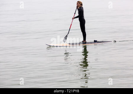 Branksome Dene, Poole, Dorset, Regno Unito. 30 Mar, 2019. Regno Unito: meteo nebuloso il sole di mattina e lo scambiatore di calore del ritardo, ma non interrompere i visitatori diretti al mare a Branksome Dene. Donna paddleboarding. standup paddleboarder standup paddle boarder Credito: Carolyn Jenkins/Alamy Live News Foto Stock