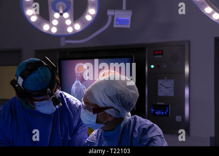 I chirurghi di parlare con ciascun altro durante un intervento chirurgico in sala operatoria in ospedale Foto Stock