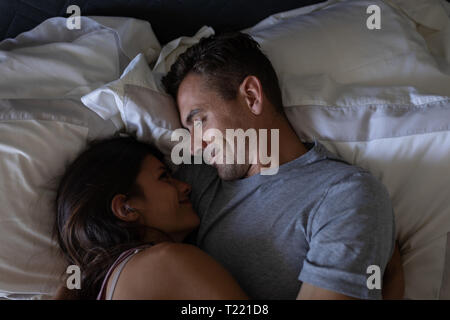 Coppia romantica guardando ogni altro mentre giaceva a letto a casa Foto Stock