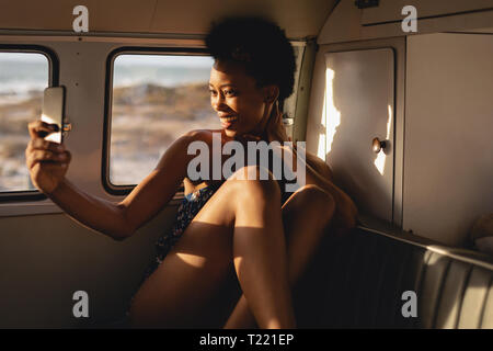 Donna africana prendendo un selfie con telefono cellulare in camper Foto Stock