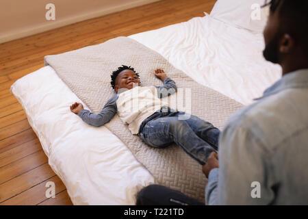 Padre e figlio godendo su letto di casa Foto Stock