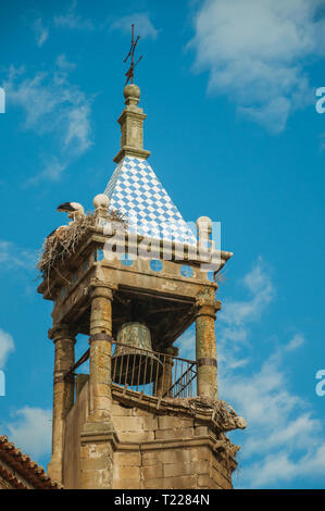 Nido di cicogne sulla parte superiore della pietra vecchia torre a soffietto con croce in ferro a Trujillo. Città natale del Conquistador Francisco Pizarro in Spagna. Foto Stock