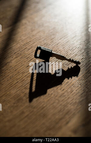 Chiave auto getta un' ombra su un tavolo di legno. Foto Stock