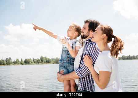 La famiglia felice è in piedi insieme e guardando verso l'alto. Il ragazzo è azienda hi figlia. Ragazza è rivolto verso l'alto e in avanti. La donna è in piedi oltre che suo marito Foto Stock