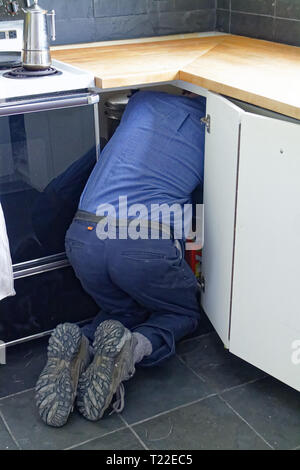 Un operaio della estremità posteriore sporge di una credenza come egli fa lavorare all interno di essa. Foto Stock