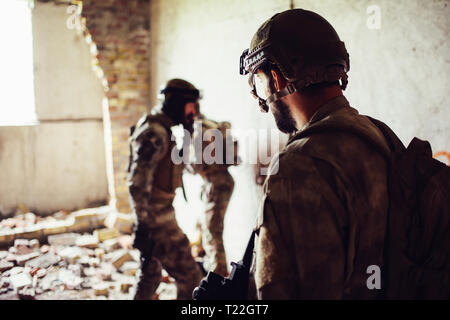 Un ppicture di soldati in piedi in un rooom vicino al muro in rovina. Due di loro sono in piedi gli uni verso gli altri mentre il terzo si guarda a loro. Essi sono Foto Stock