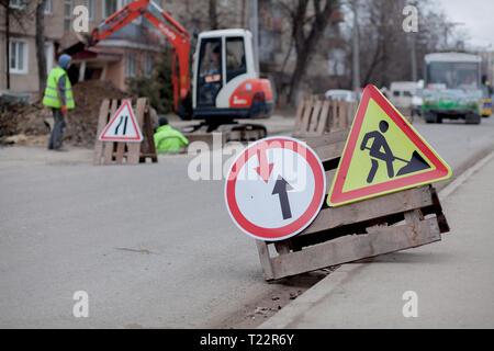 Segnaletica stradale, deviazione, riparazione su strada su strada, sfondo carrello escavatore e foro di scavo. Foto Stock