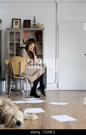 Giovane donna seduta alla sua scrivania, pensando Foto Stock