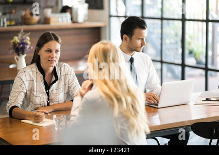 I colleghi per discutere e lavorare sul computer portatile sul tavolo di legno in cafe Foto Stock