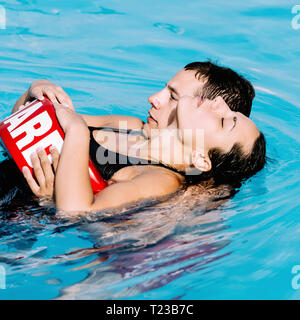 Bagnino aiutando una donna dopo il nuoto incidente. Foto Stock