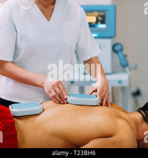 Magnetoterapia. Fisioterapista immissione magneti sulla schiena del paziente. Foto Stock