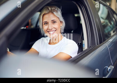 Giovane donna seduta nella sua auto Foto Stock