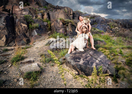 Primitivo persone vestite di pelle di animale in pietra con antica grotta disegno in montagna Foto Stock