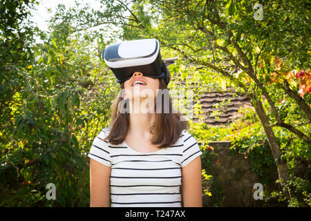 Ragazza stupito indossando occhiali per realtà virtuale in giardino Foto Stock