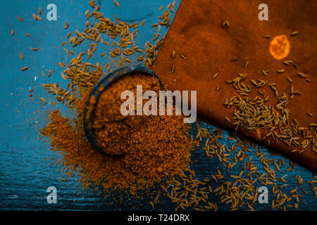 Close up di cumino in polvere o zeera o jeera con cumino grezzo su una superficie di legno in un vaso di argilla su un panno o un tovagliolo. Foto Stock