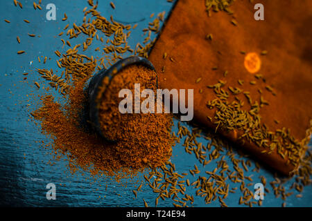 Close up di cumino in polvere o zeera o jeera con cumino grezzo su una superficie di legno in un vaso di argilla su un panno o un tovagliolo. Foto Stock