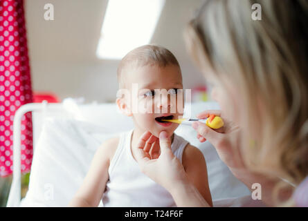 Madre tenendo la temperatura del bimbo figlio a casa Foto Stock