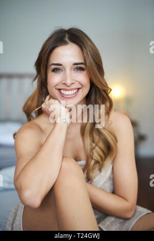 Ritratto di felice giovane donna seduta sul letto Foto Stock