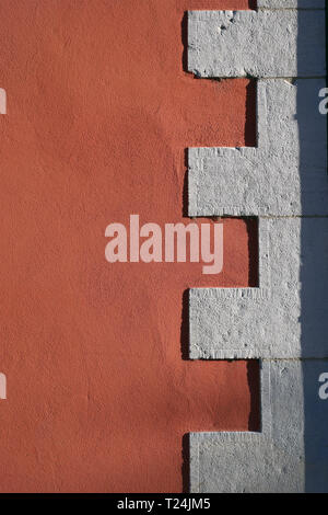 Dettagli interessanti di un edificio. Vi è una parete esterna di un edificio che è dipinto di rosso / arancio e alcune mattonelle bianche. Foto Stock