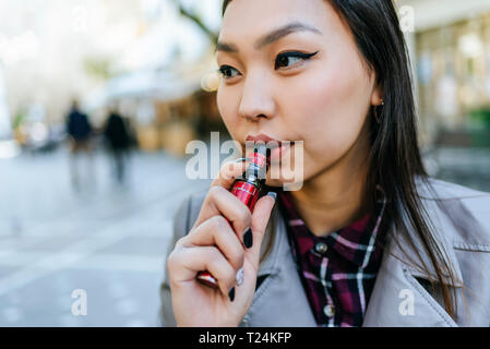 Giovane donna di fumare sigaretta elettronica Foto Stock