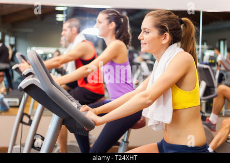 Le persone felici facendo indoor bike in un fitness club Foto Stock