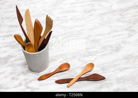 In legno fatti a mano utensili in una coppa di calcestruzzo, su sfondo marmo con copia spazio. Foto Stock