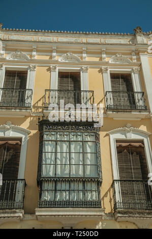 Finestre con balcone sulla facciata del palazzo in stile eclettico con ornamenti a Merida. La città conserva molti edifici della Roma antica in Spagna. Foto Stock