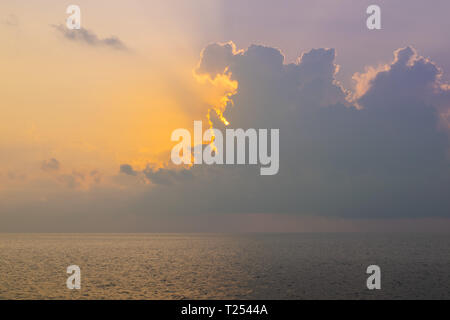 Il sole è in aumento in corso di nubi e filtrando attraverso, oltre il mare delle Andamane in Thailandia. Foto Stock