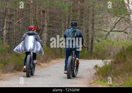 I ciclisti in bicicletta lungo la strada forestale in Glenmore Forest Park nel Parco Nazionale di Cairngorms durante la molla a secco Meteo Aviemore Scozia, Regno Unito Foto Stock