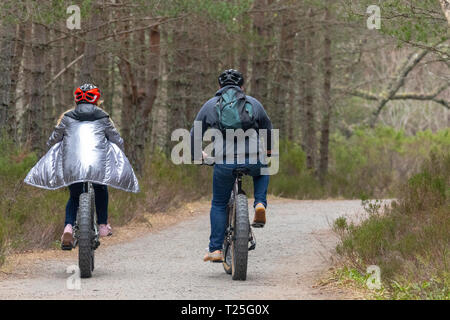 I ciclisti in bicicletta lungo la strada forestale in Glenmore Forest Park nel Parco Nazionale di Cairngorms durante la molla a secco Meteo Aviemore Scozia, Regno Unito Foto Stock