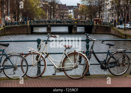 Il pedale biciclette parcheggiate su un ponte che si affaccia sul canale di Amsterdam Olanda. Foto Stock