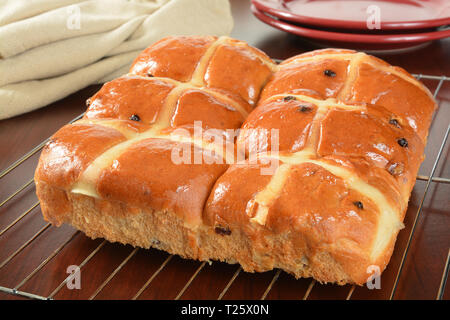 Freschi di forno hot cross panini e rabboccato con smalto di colore arancione su una griglia di raffreddamento. Un cibo tradizionalmente associato con il Venerdì Santo Foto Stock