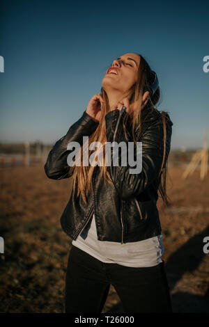 Felice giovane donna ascoltando musica con le cuffie all'aperto Foto Stock