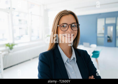 Ritratto di un fiducioso giovane imprenditrice, stando in ufficio Foto Stock