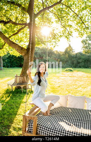 Donna matura rilassante su un letto sospeso in giardino Foto Stock