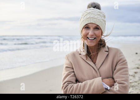 Spagna, Menorca, ritratto di felice senior donna sulla spiaggia in inverno Foto Stock
