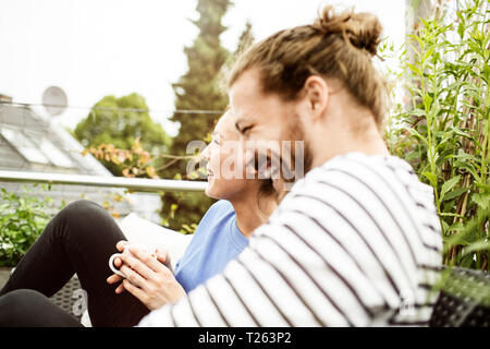 Coppia giovane rilassante sul proprio balcone, bere caffè Foto Stock