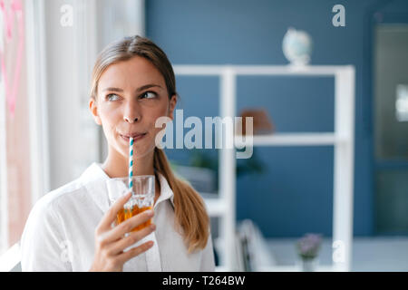 Giovane donna bere il tè con una paglia Foto Stock