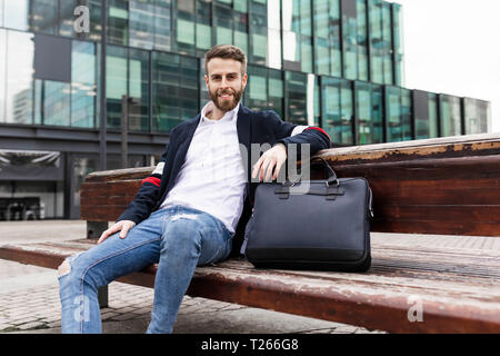 Ritratto di sorridente imprenditore elegante seduta su una panchina in città Foto Stock
