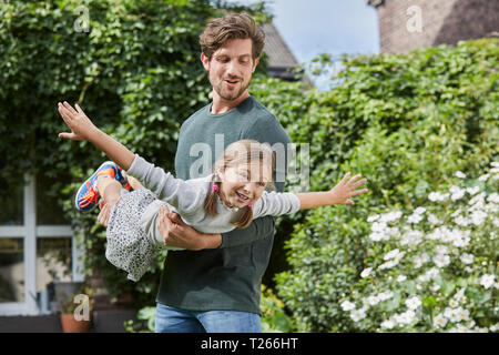 Padre Felice giocando con la figlia nel giardino della loro casa Foto Stock