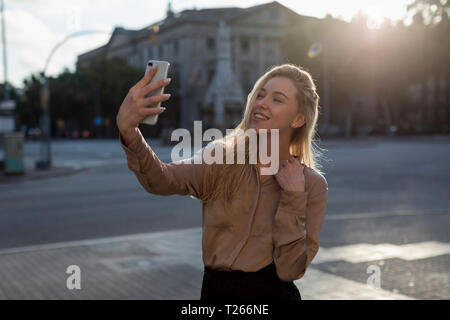 Felice giovane donna prendendo un selfie nella città Foto Stock
